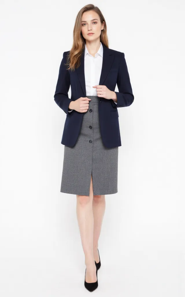 A French female model wearing Business   style clothing, against a white background, in a front   facing shot focusing on shoes